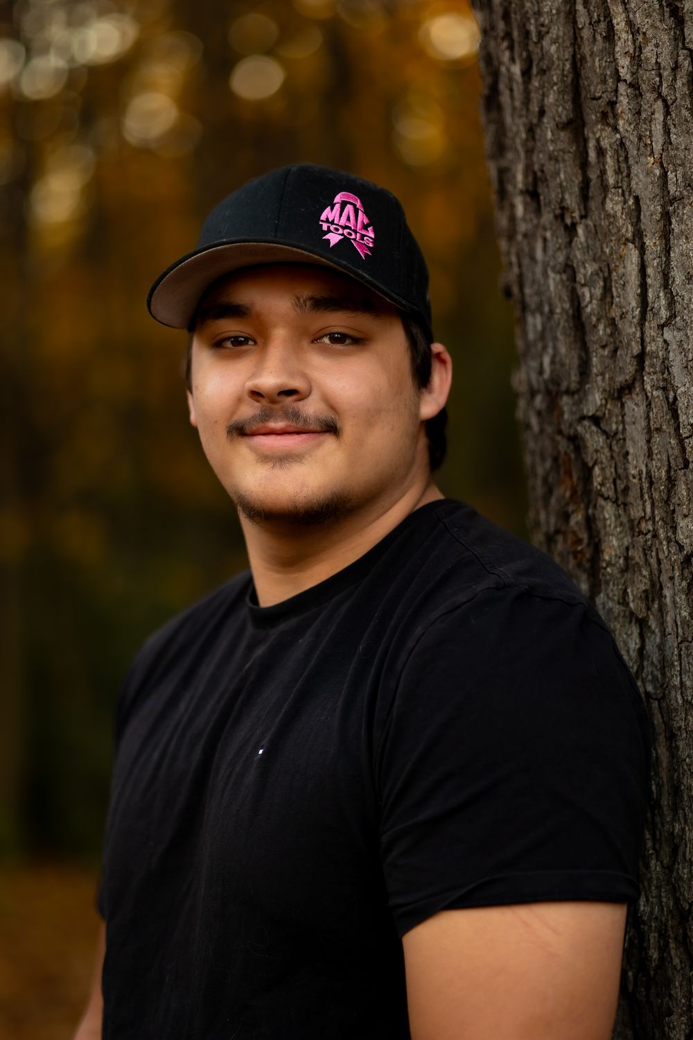 Portrait series showing someone in a black t-shirt and baseball cap against a blurred autumn forest background.