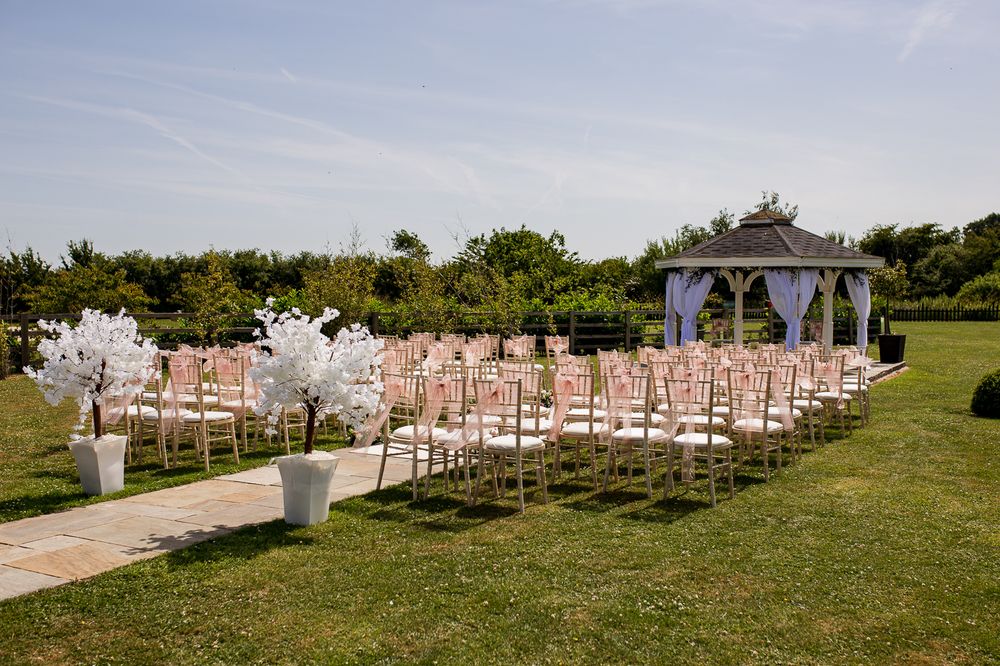 Panoramic view of wedding ceremony setup with white chairs and gazebo.