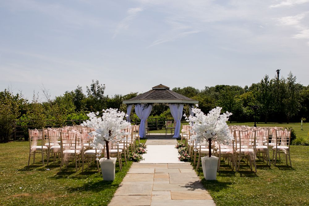 Outdoor wedding ceremony setup with white chairs and floral decorations.