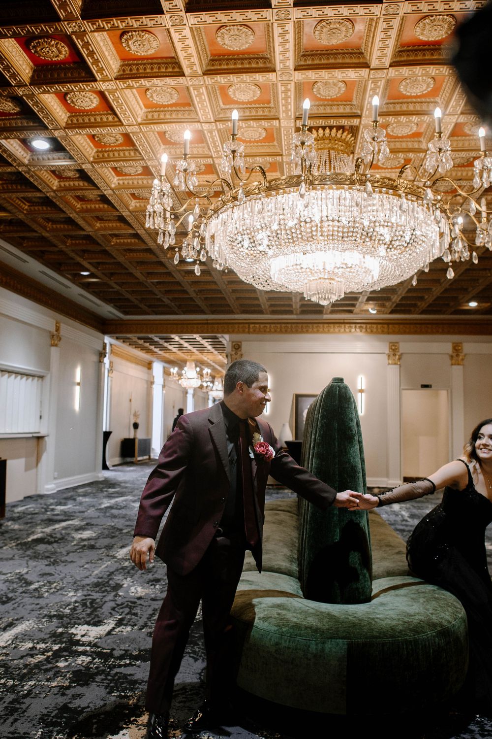 Interior photoshoot setup in an opulent room featuring crystal chandeliers and emerald velvet furniture.