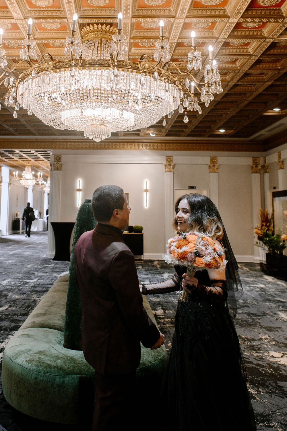 Elegant ballroom with crystal chandeliers and ornate decor showing multiple perspectives of a dark couch setup.
