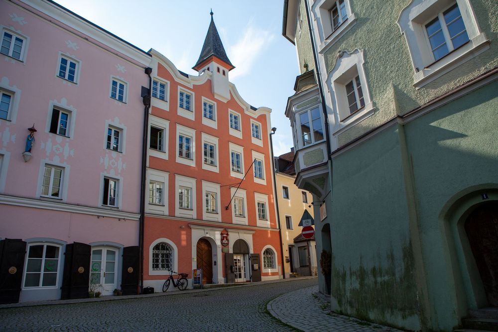 Charming narrow cobblestone street with colorful historic buildings and a church spire in a European town center.
