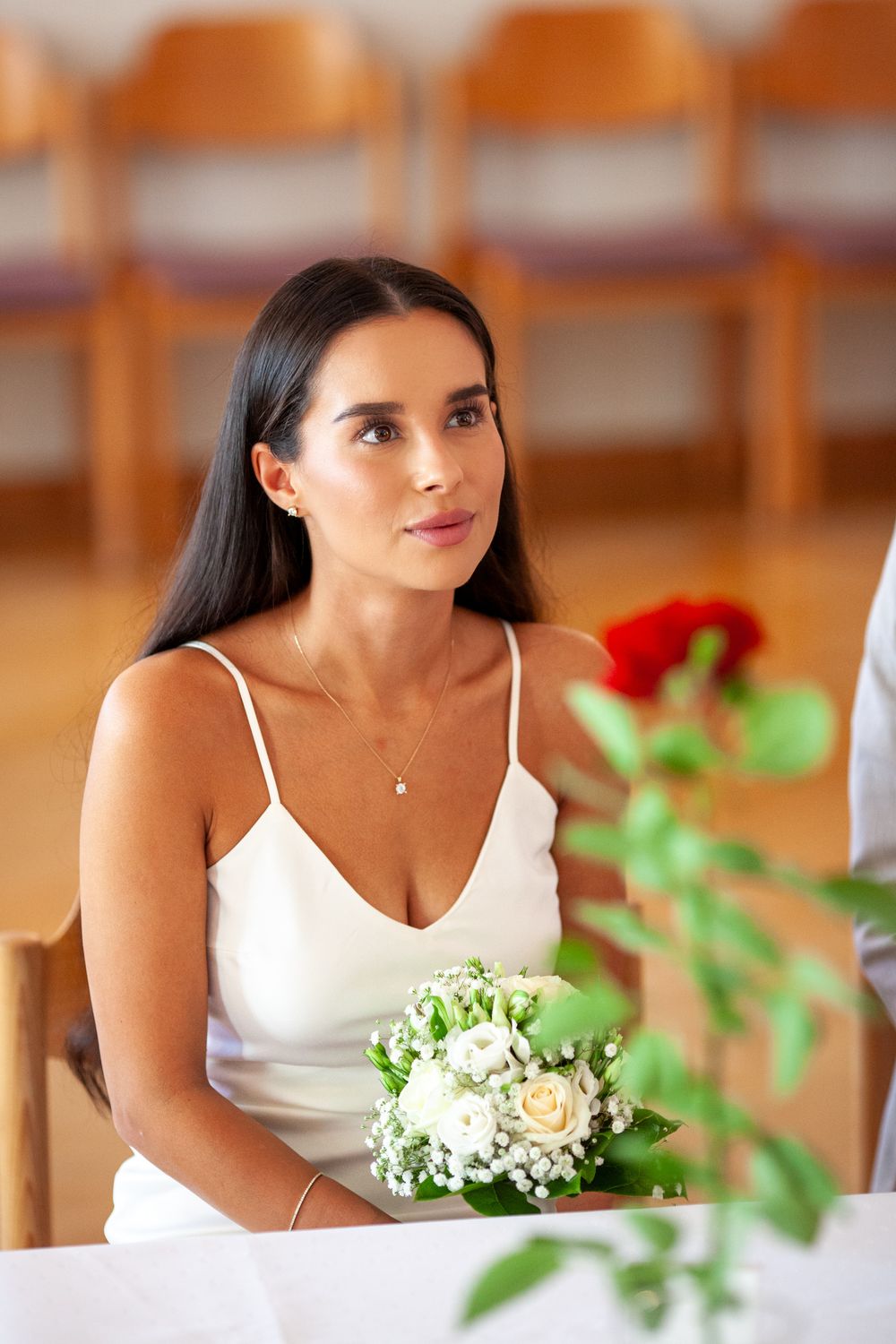 Woman in white dress sitting at a table with flowers and delicate decor in a warm-lit setting.