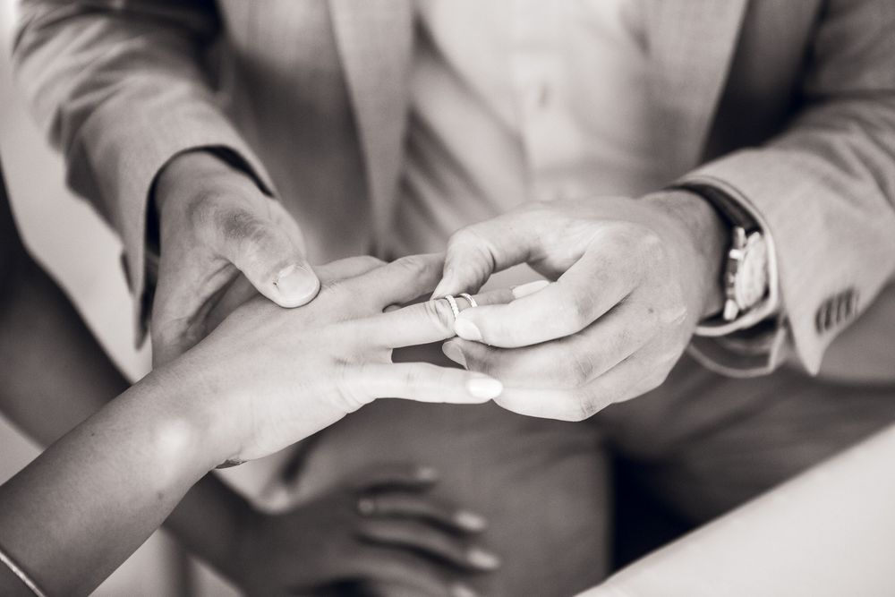 Close-up black and white photo of hands gently holding a baby's tiny fingers and hand.