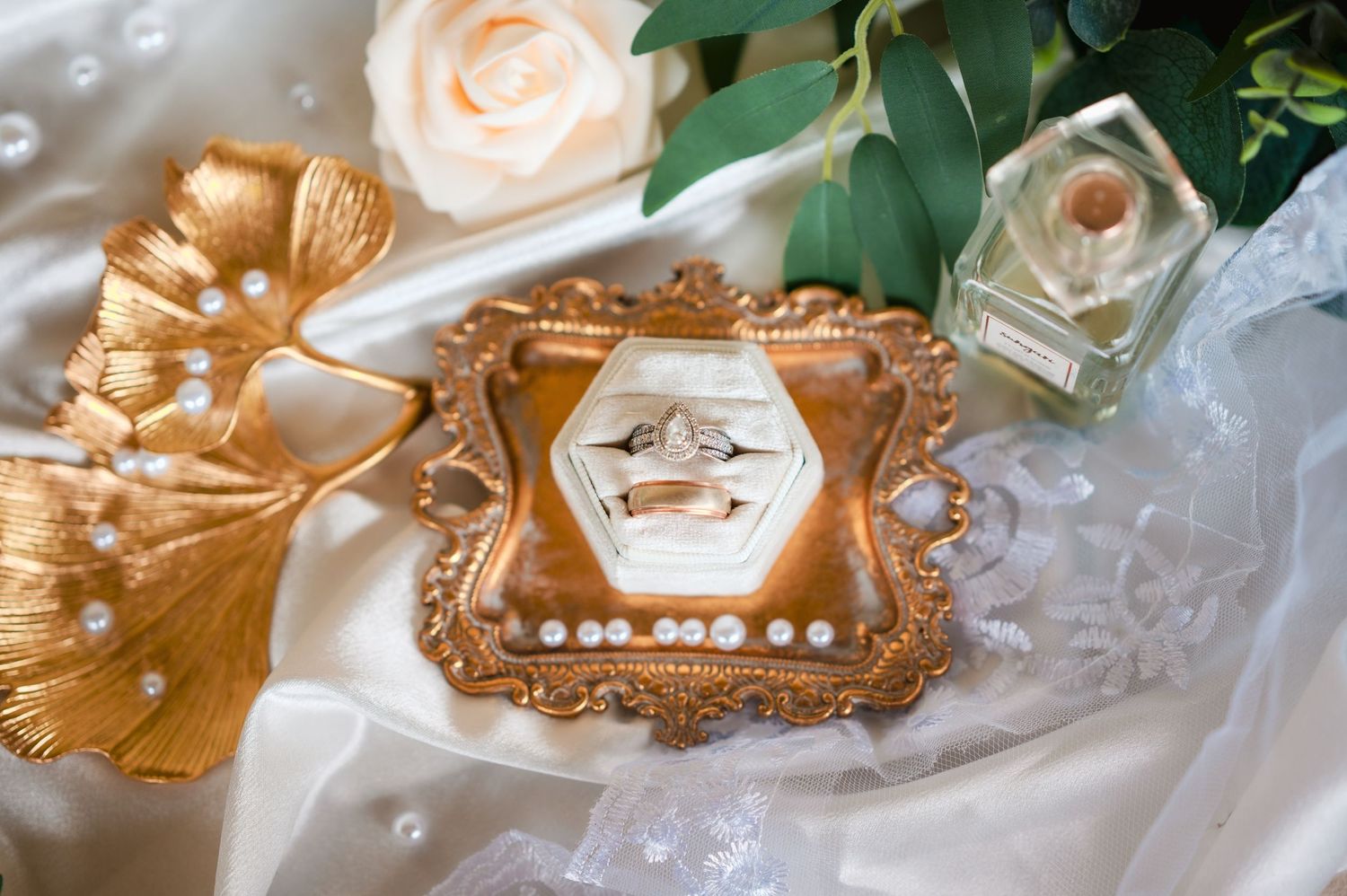 Delicate gold and blush wedding place cards with ornate frames and floral accents rest on a white linen tablecloth.