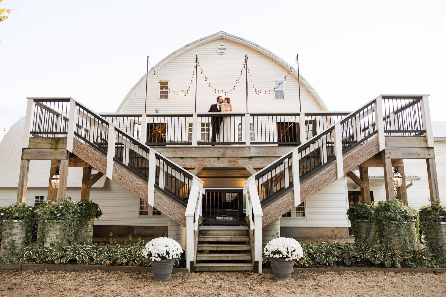 Rustic white barn wedding venue with charming stairs and classic architecture.