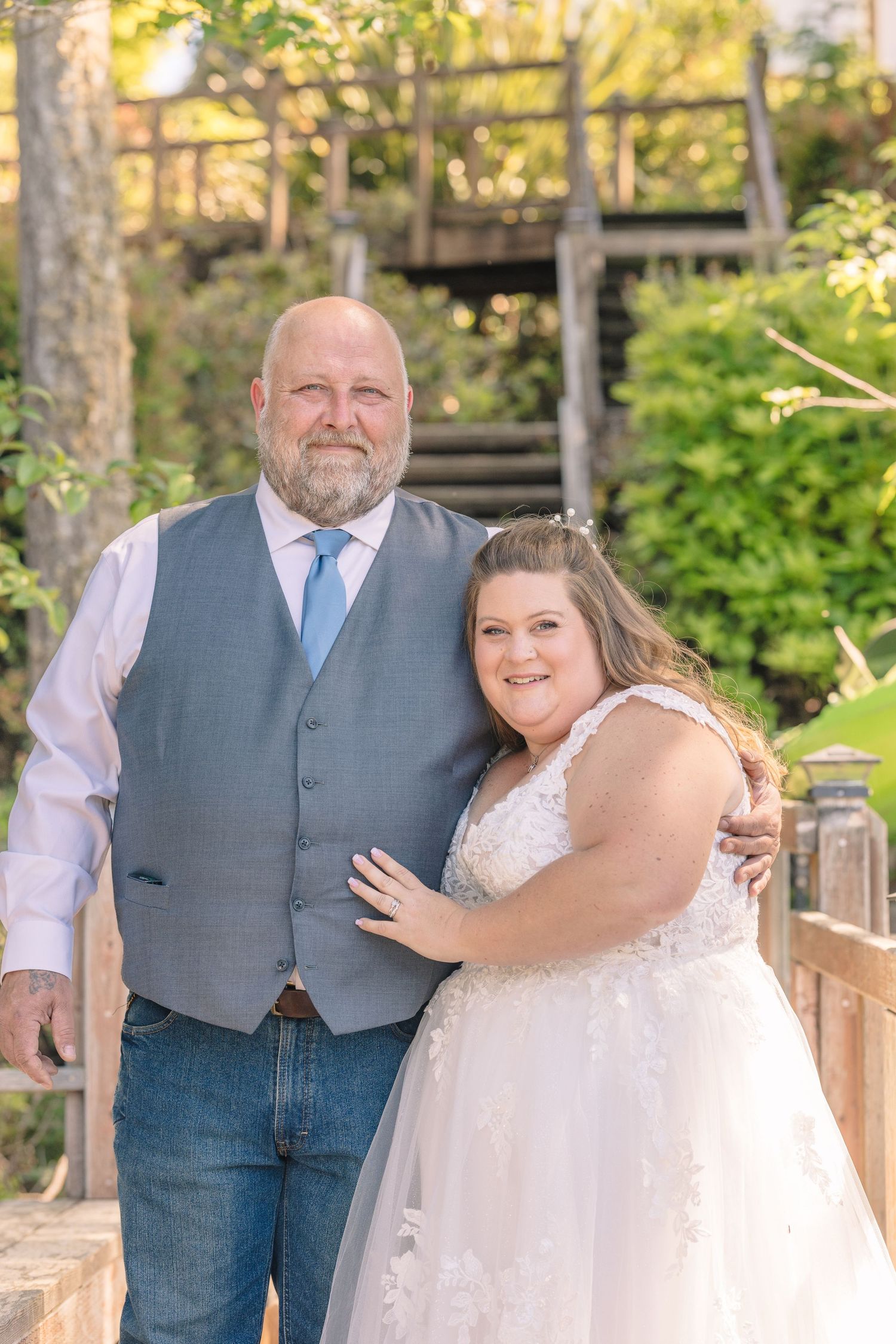 Couple poses together on wooden bridge during outdoor wedding photoshoot.