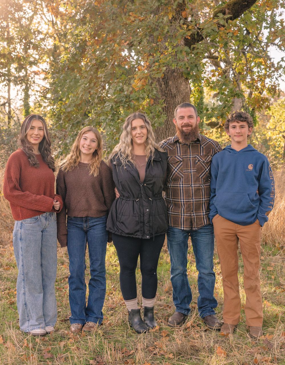 Group portrait of people standing in a line against autumn trees.