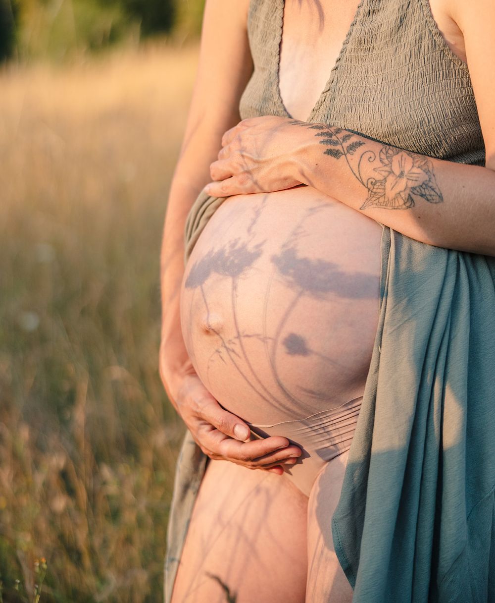 Maternity photos showing close-up details of pregnant belly in soft evening light.