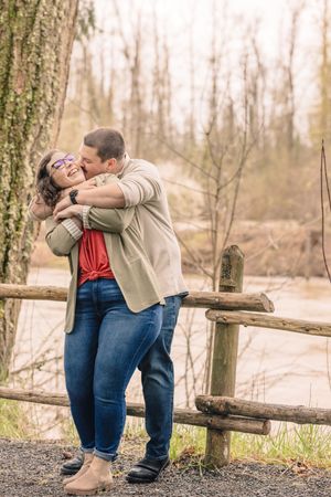 Couple sharing a romantic moment by a rustic wooden fence.