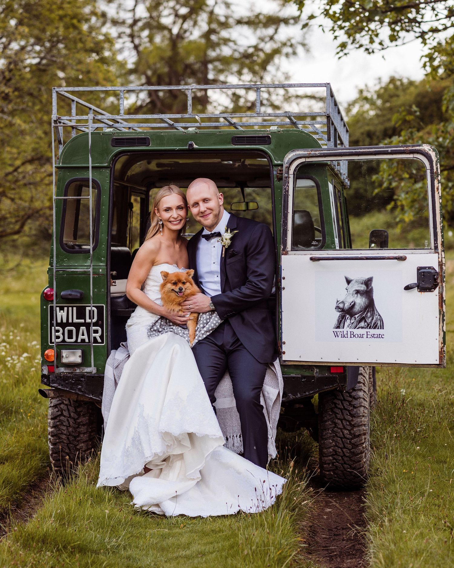 A romantic wedding couple poses with a vintage green military truck in a rustic outdoor setting.