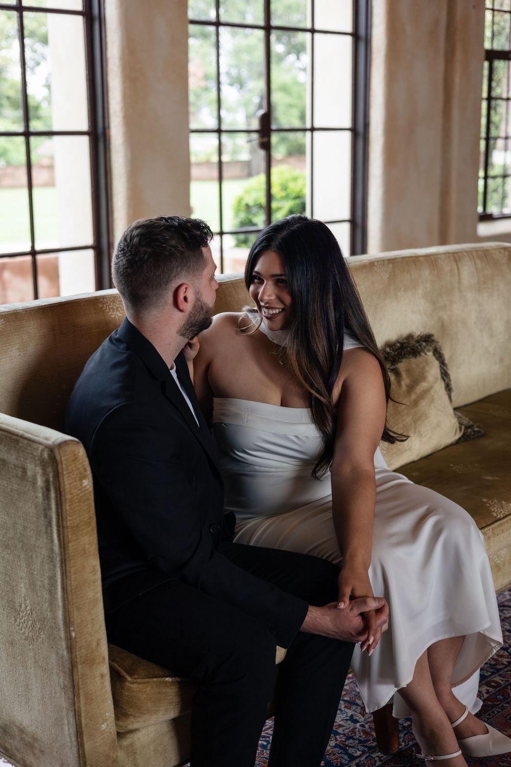 A romantic sequence of photos showing a couple sharing intimate moments on a brown couch in a sunlit room.