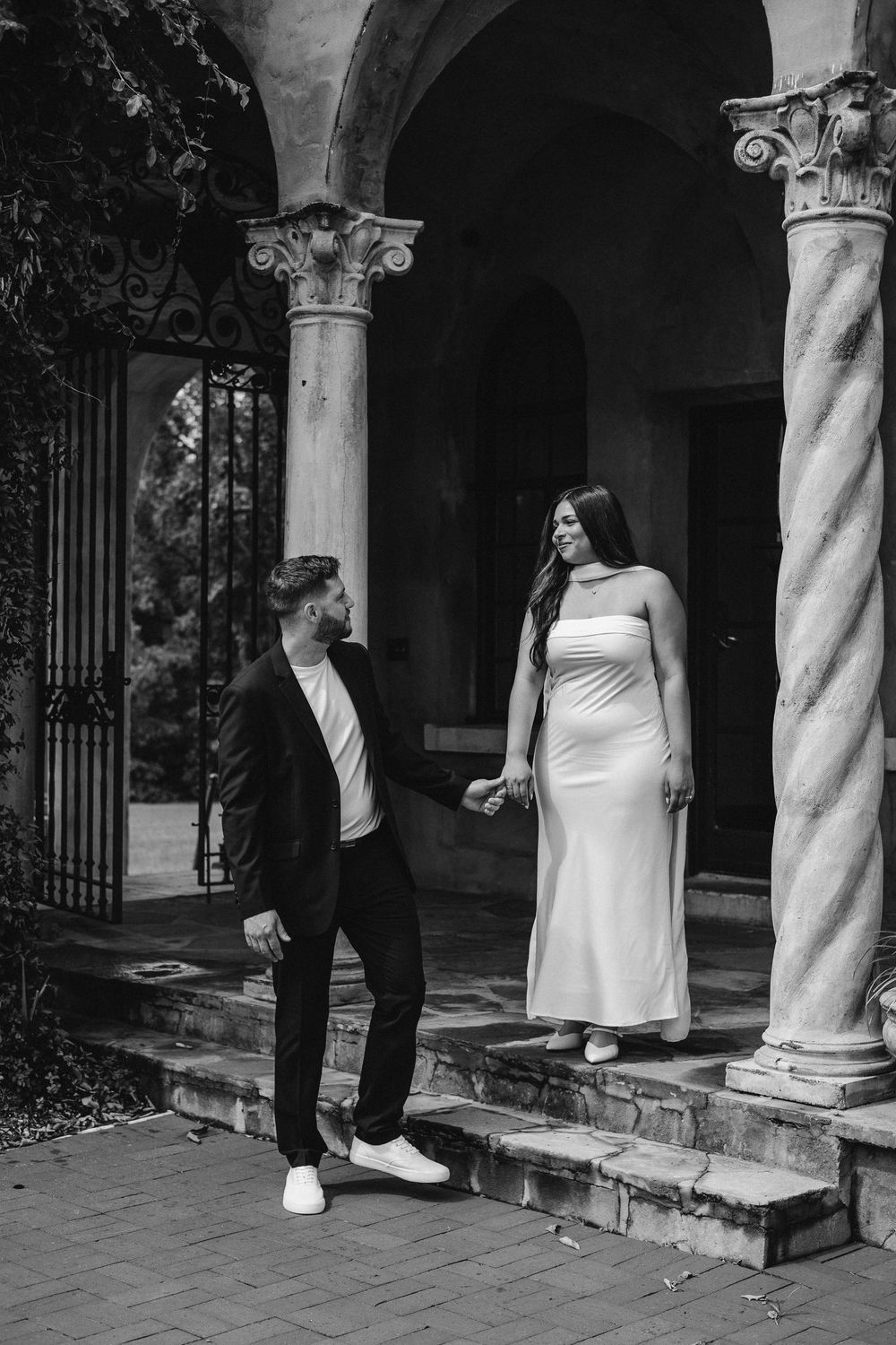 A sequence of black and white photos showing a couple walking through an arched colonnade with ornate columns.