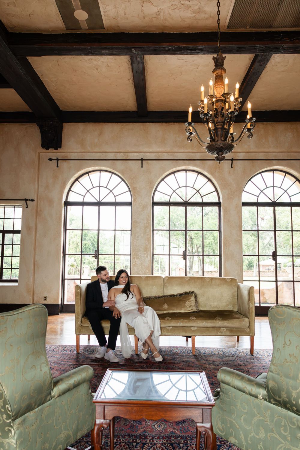 Elegant vintage room with arched windows, exposed beams, and antique furniture creates a romantic atmosphere.
