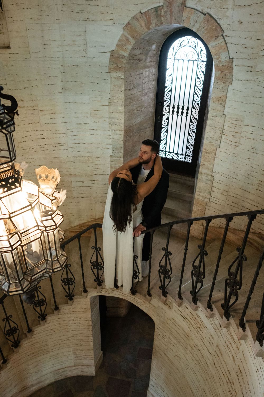 Curved stone staircase with ornate iron railings in a historic building interior.