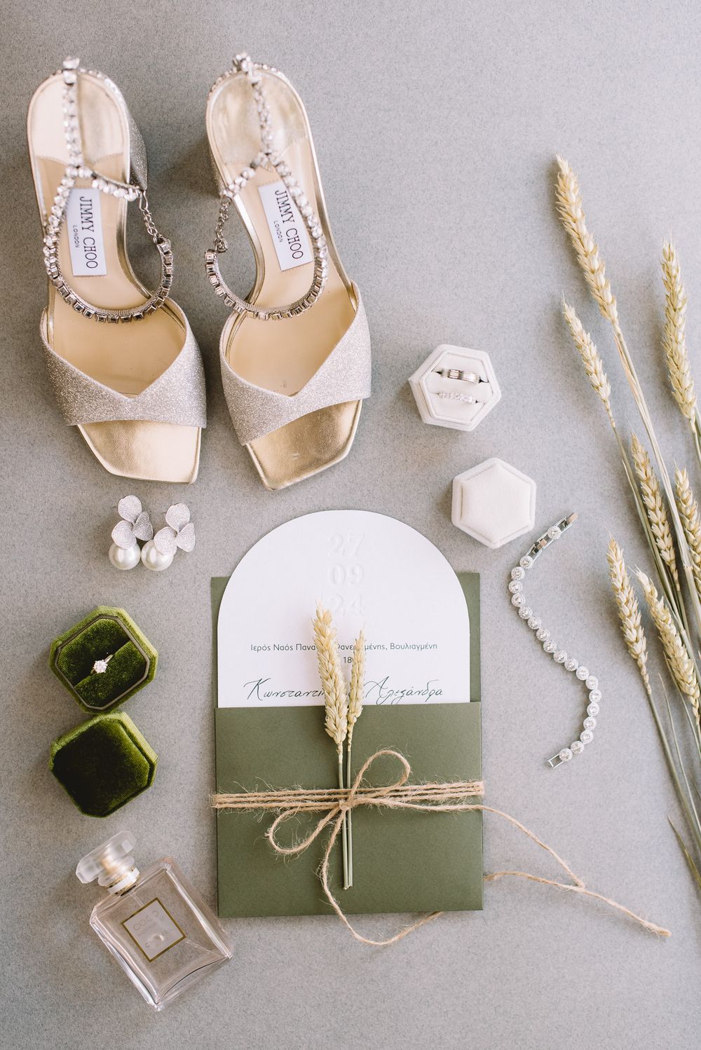 Elegant wedding details featuring nude Jimmy Choo sandals, green velvet ring boxes, invitation suite and dried wheat stems.