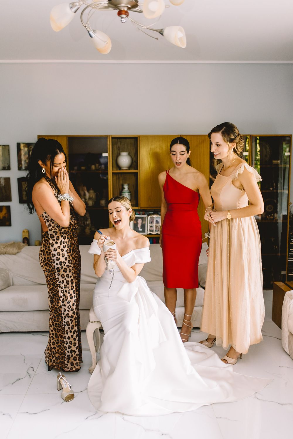 A sequence of candid dance shots showing wedding party members in beige dresses and white gowns celebrating on a light floor.