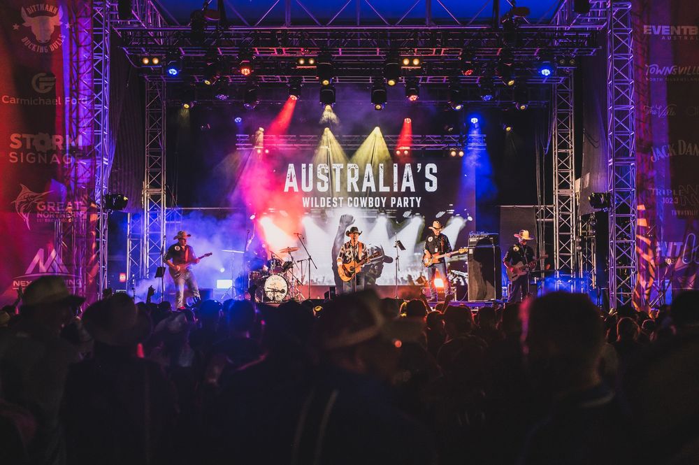 Live band performs on stage at Australia's Wildest Cowboy Party with colorful lights and crowd.