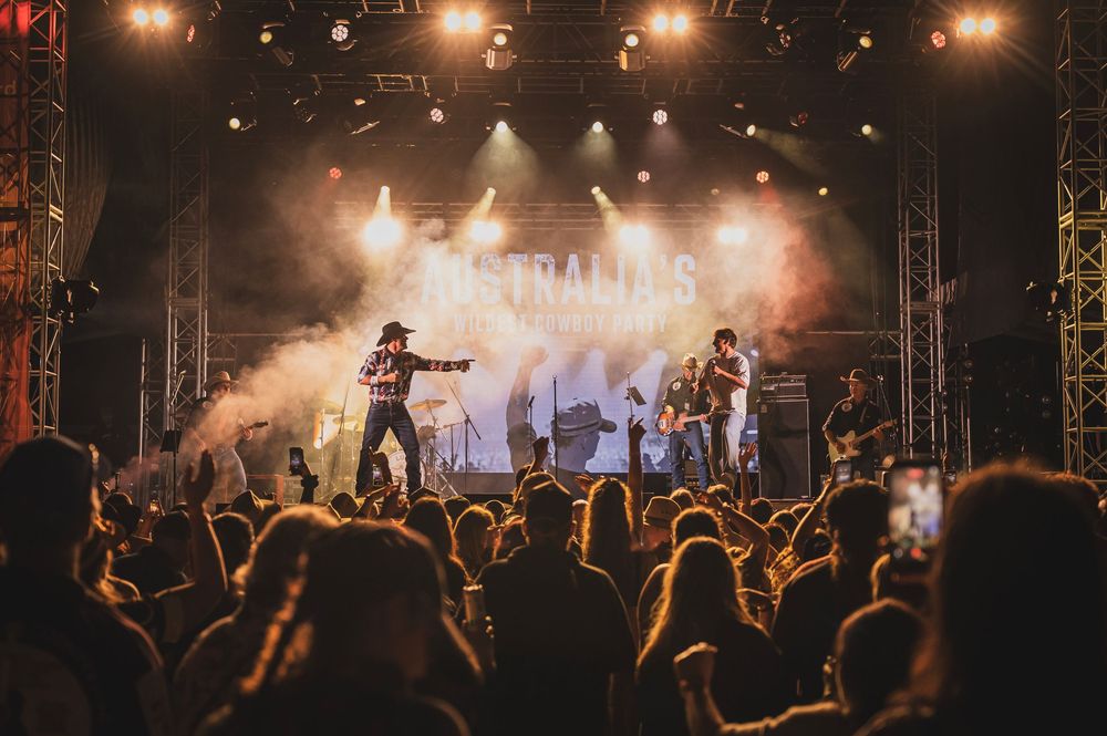 Live concert performance on a smoky stage with a crowd of fans watching a band perform under bright lights.