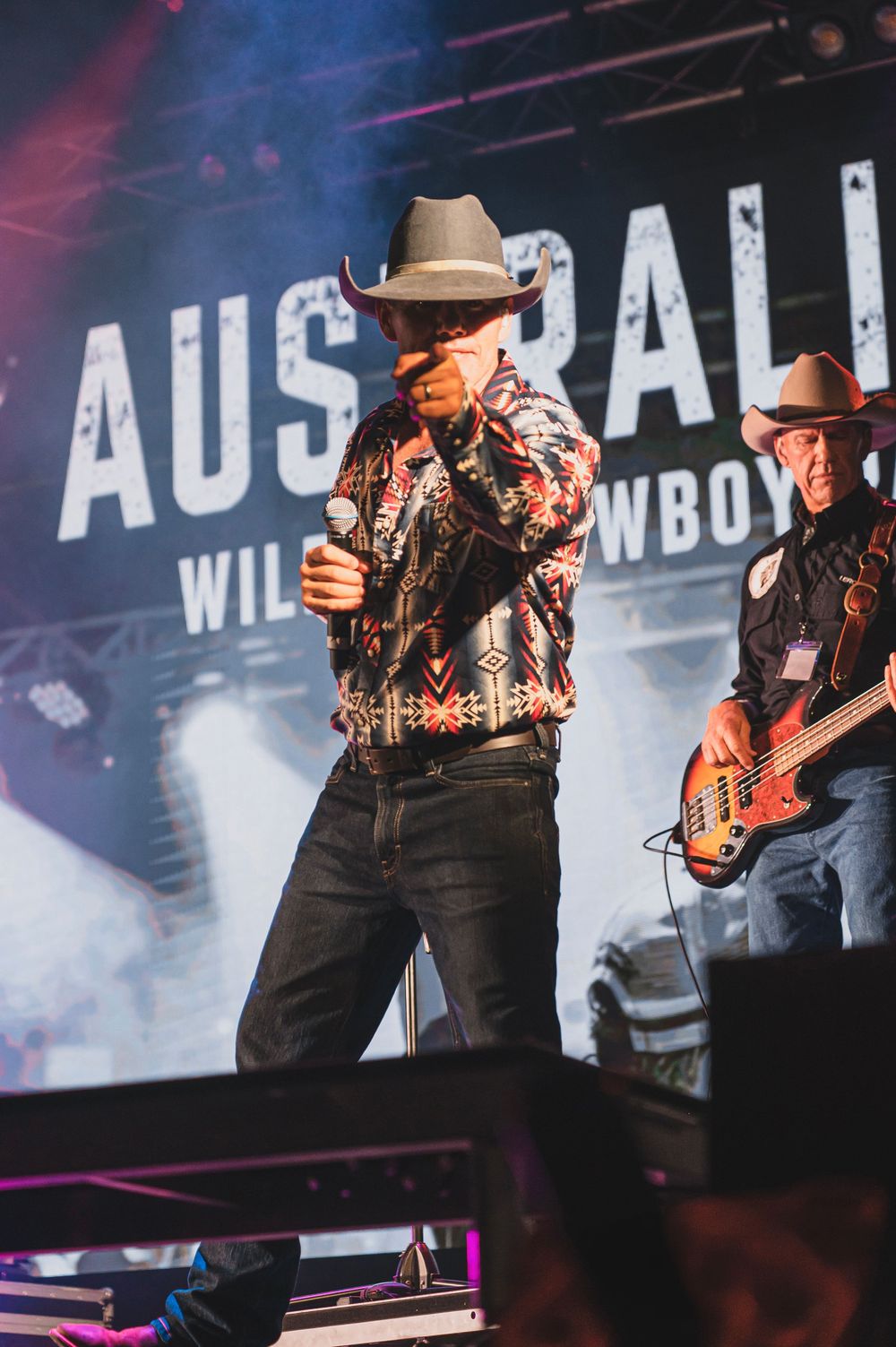 Two country musicians perform on stage at Australian Wild West Cowboys show, wearing cowboy hats and western attire.
