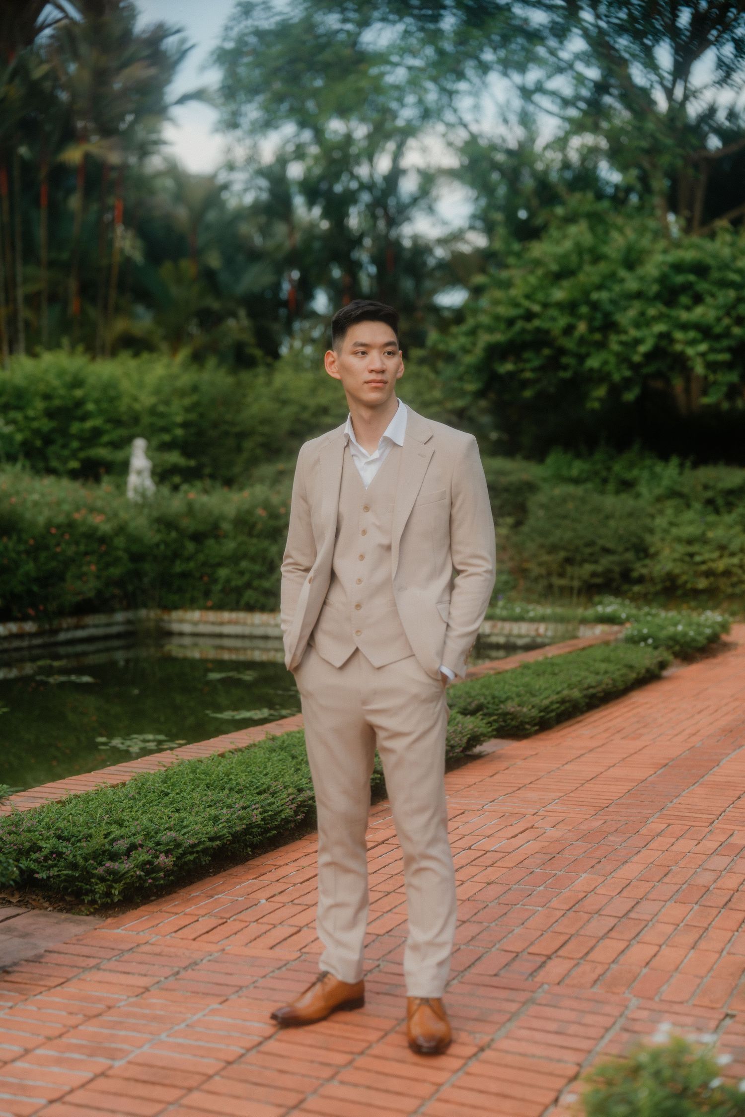 A collection of ten photos showing someone in a beige suit and brown shoes posing on a brick pathway in a garden setting.