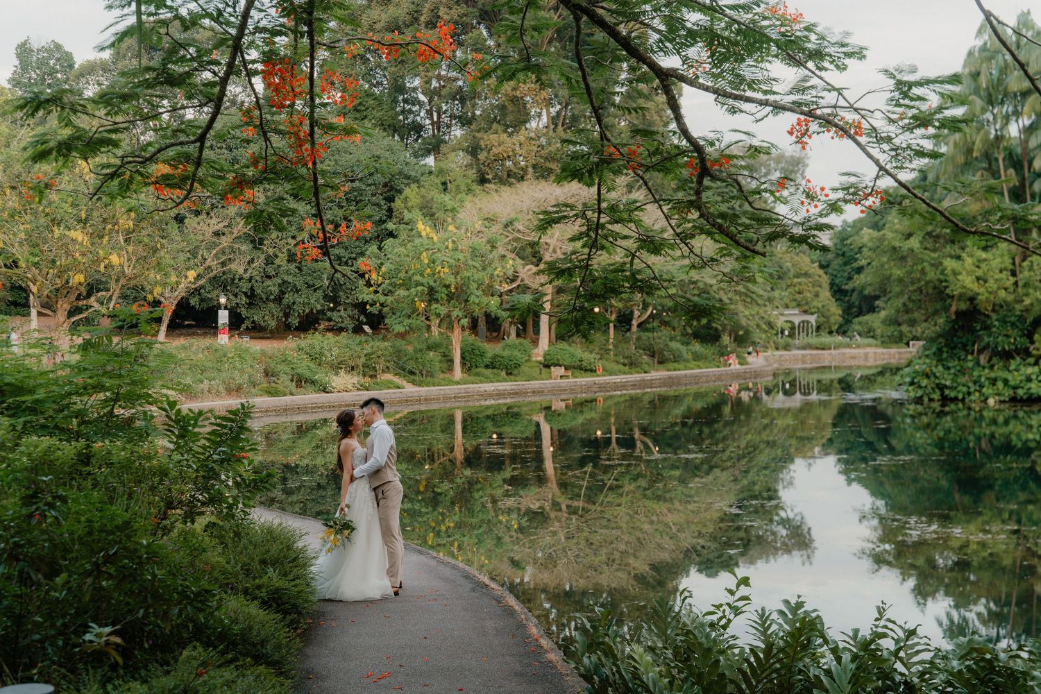A series of romantic wedding photographs captured in a lush green garden setting with a meandering path and tranquil pond.