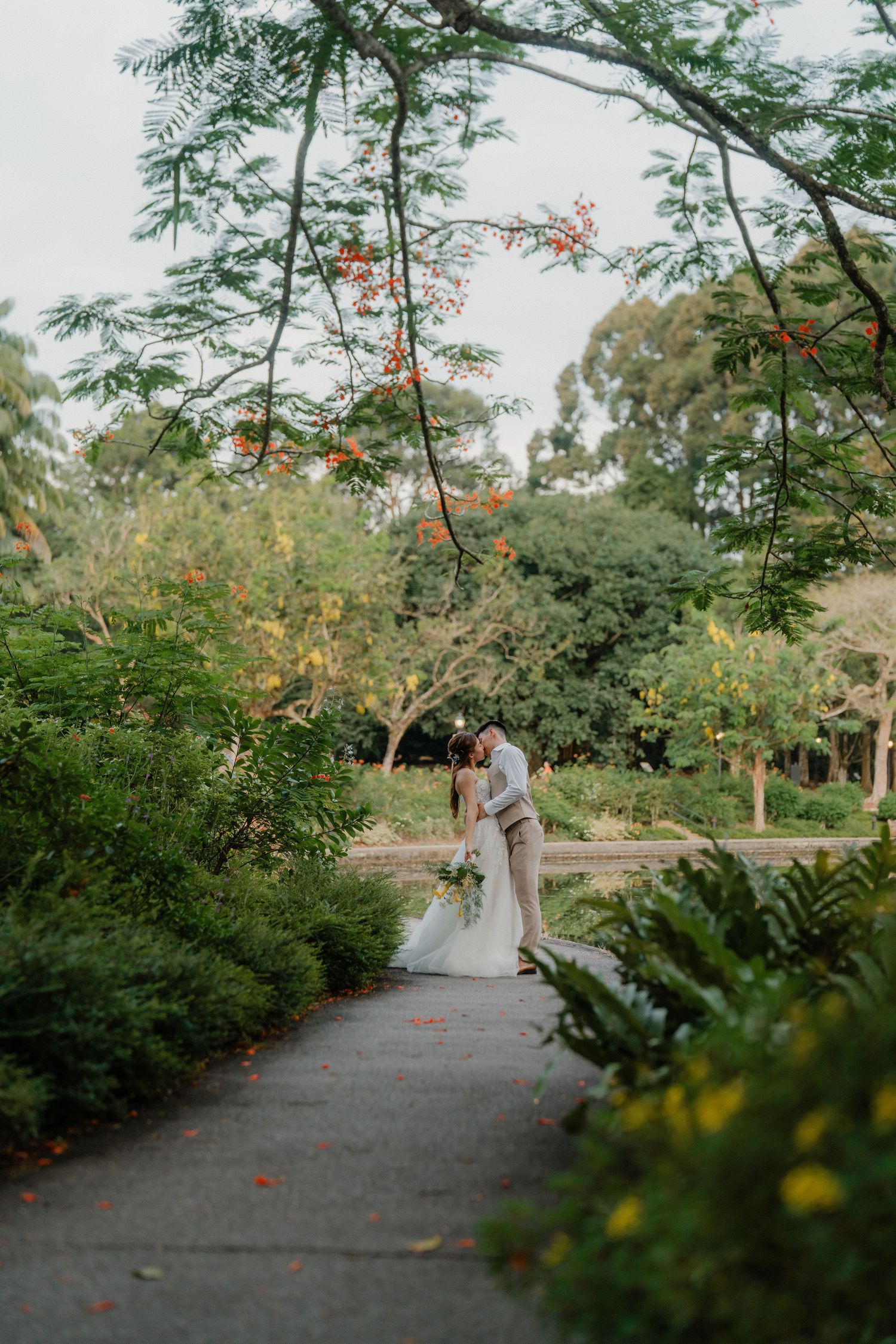 A garden pathway lined with blooming tropical trees and foliage creates a scenic backdrop.