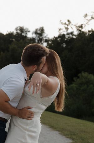 A romantic sunset moment between a couple in white and denim on a grassy path.