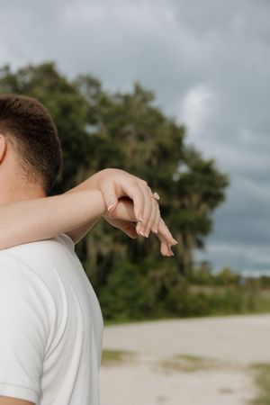 Close-up detail of hands reaching toward each other against a cloudy sky.