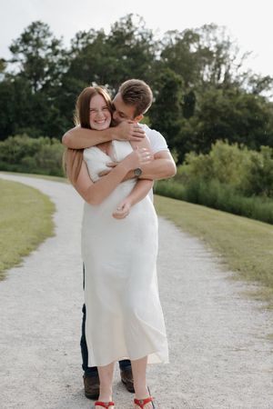 A sweet embrace captured on a winding path with lush greenery in the background.