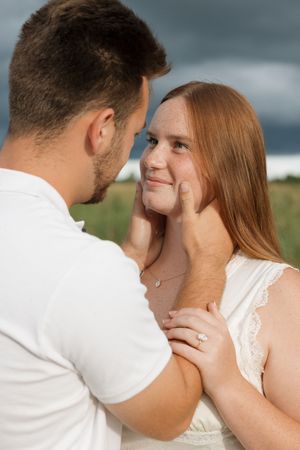 An intimate close-up moment between a couple in white against a moody sky.