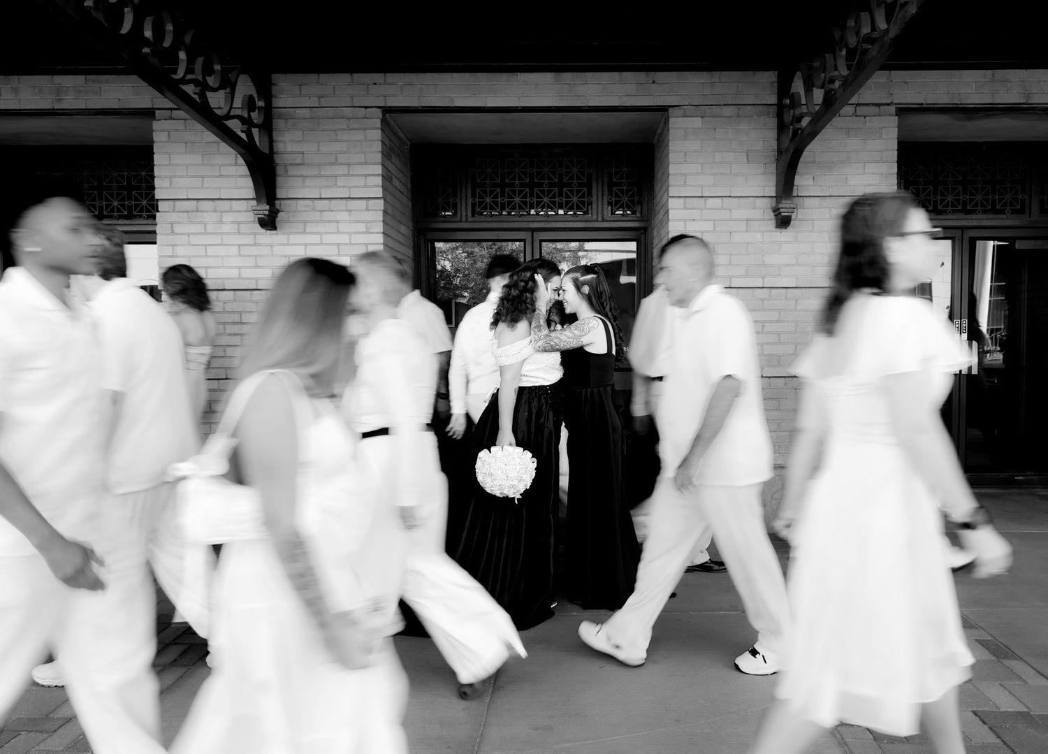 A joyful couple celebrates their tropical wedding day on a palm-lined pathway in elegant attire.