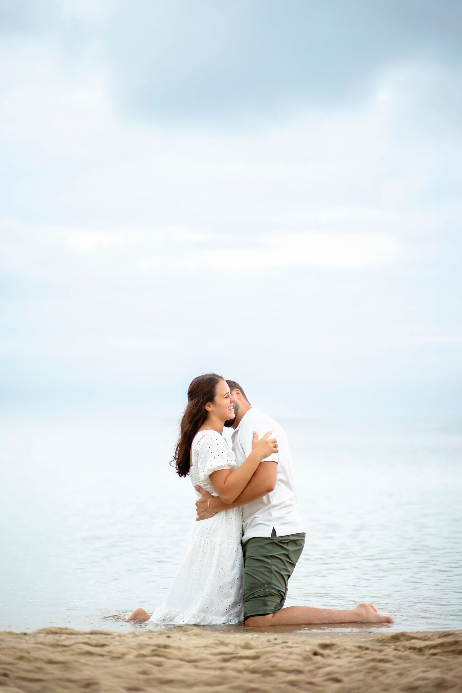 A romantic proposal scene set between rows of grapevines in a scenic vineyard with white flowers and a blanket.