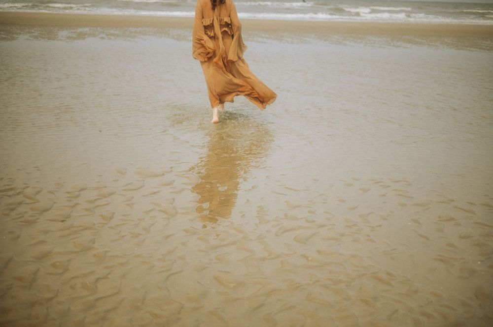 Silhouettes of movement captured across a sandy beach at low tide.