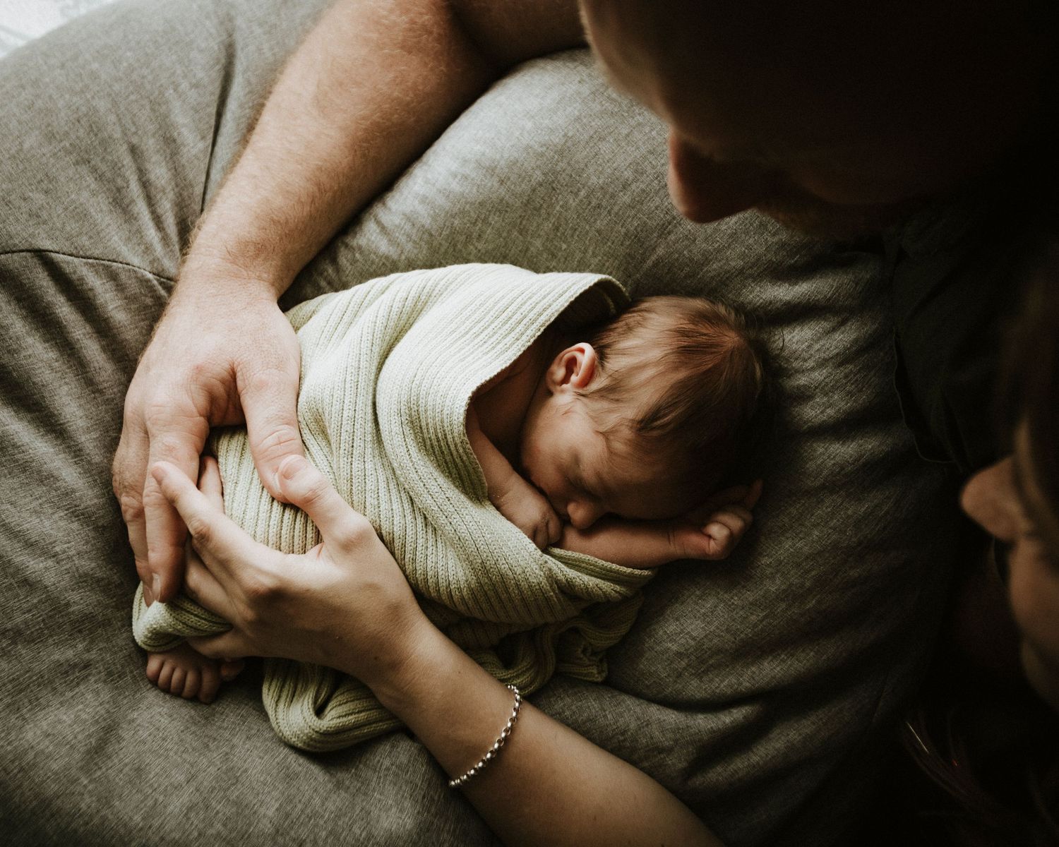 A newborn baby swaddled being cradled by his parents for their newborn session.