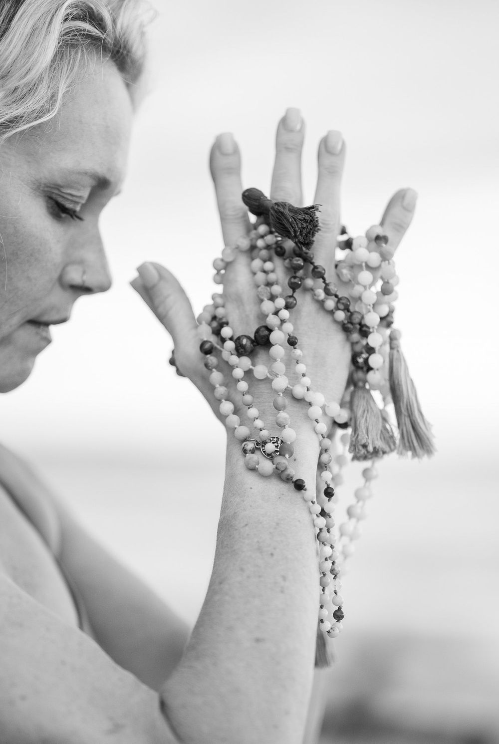 Black and white portrait showing hands holding prayer beads in meditation.
