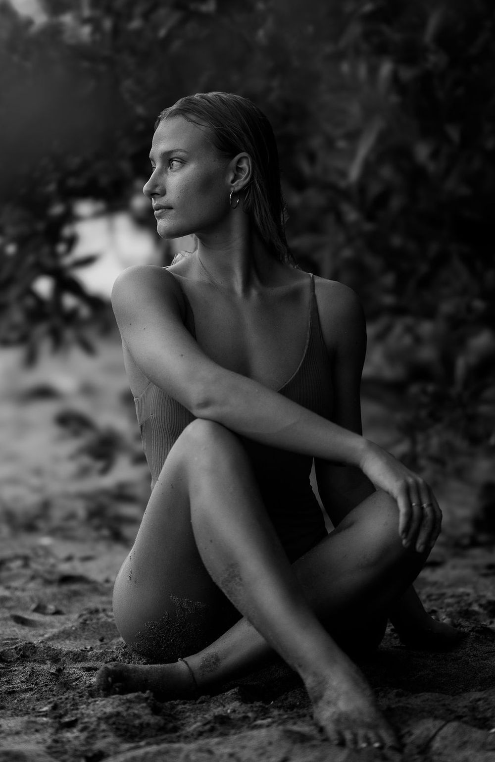 Artistic black and white portrait series showing a figure in various graceful reclining poses outdoors.