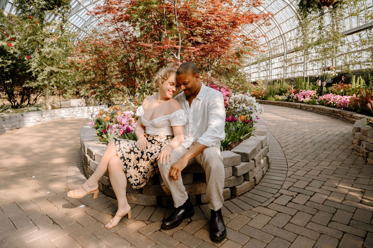 A family enjoys a peaceful moment together on a garden bench surrounded by lush greenery in a botanical setting.