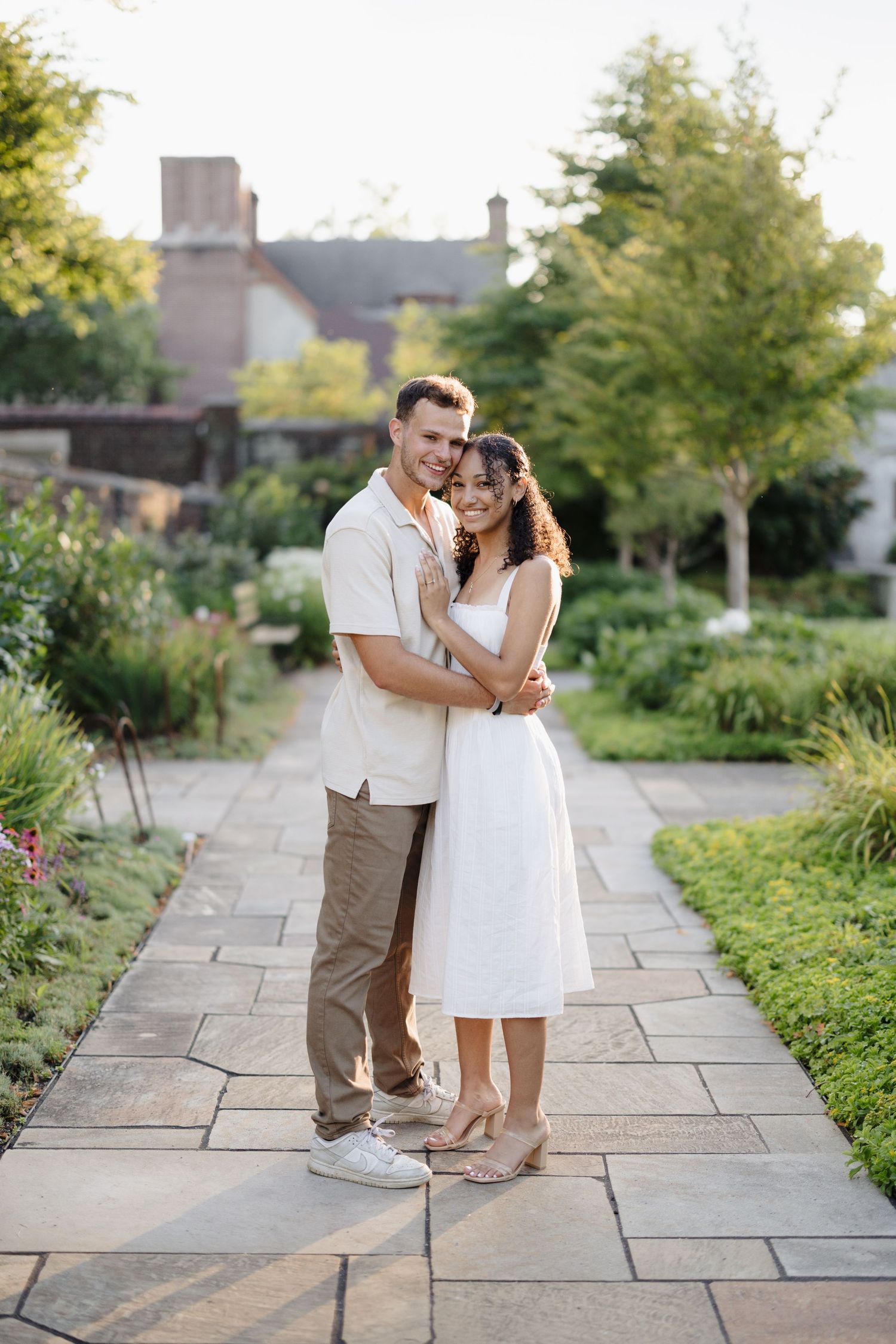 Couple shares romantic moments along a stone garden pathway during an outdoor photo session.