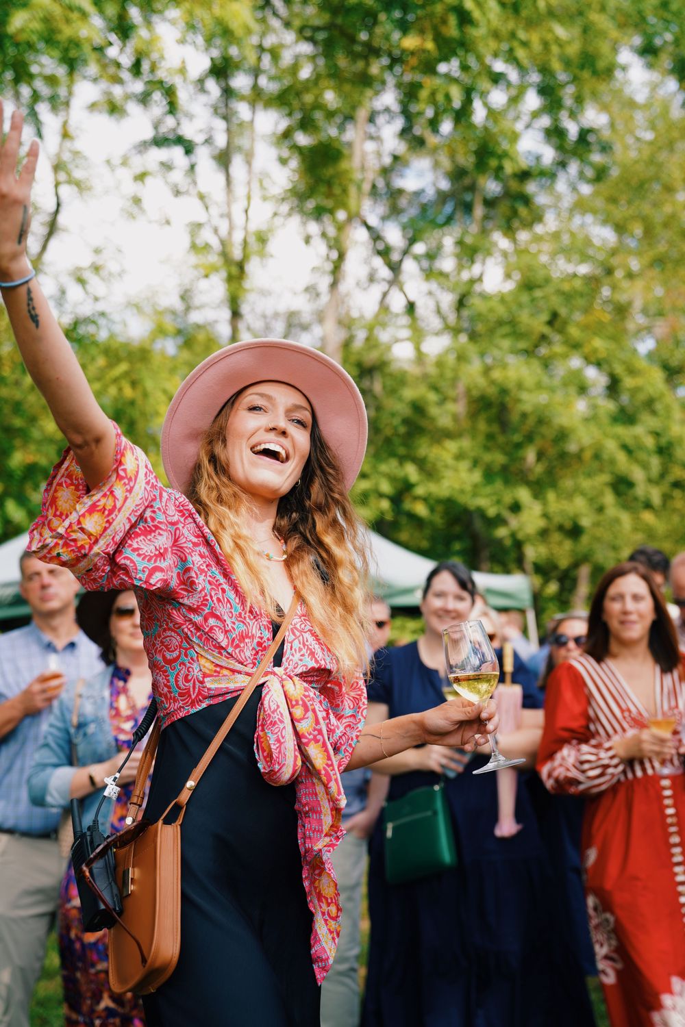A festive outdoor gathering with attendees enjoying drinks and celebrations in a park setting.