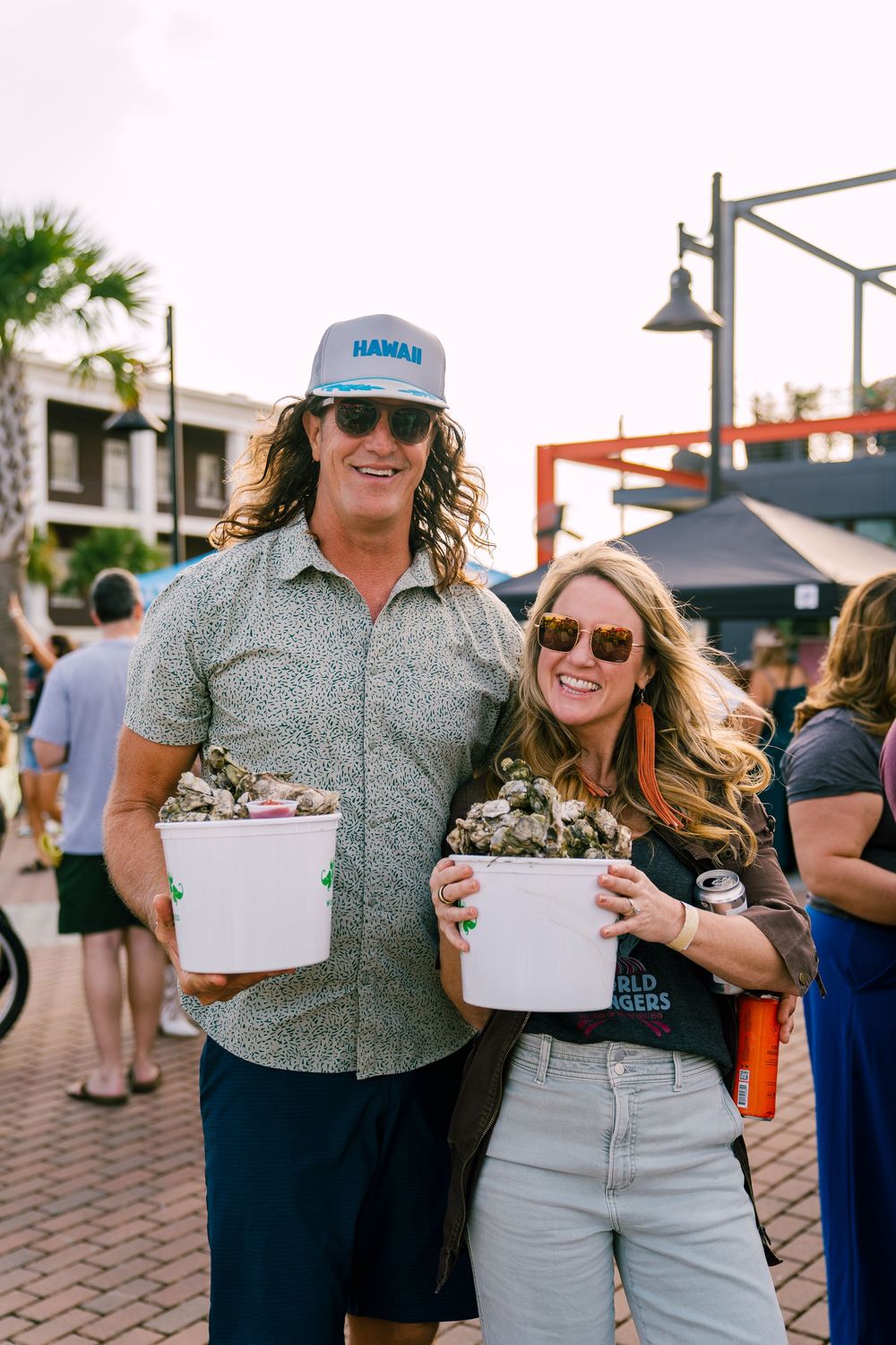 Two people holding food containers at outdoor market.