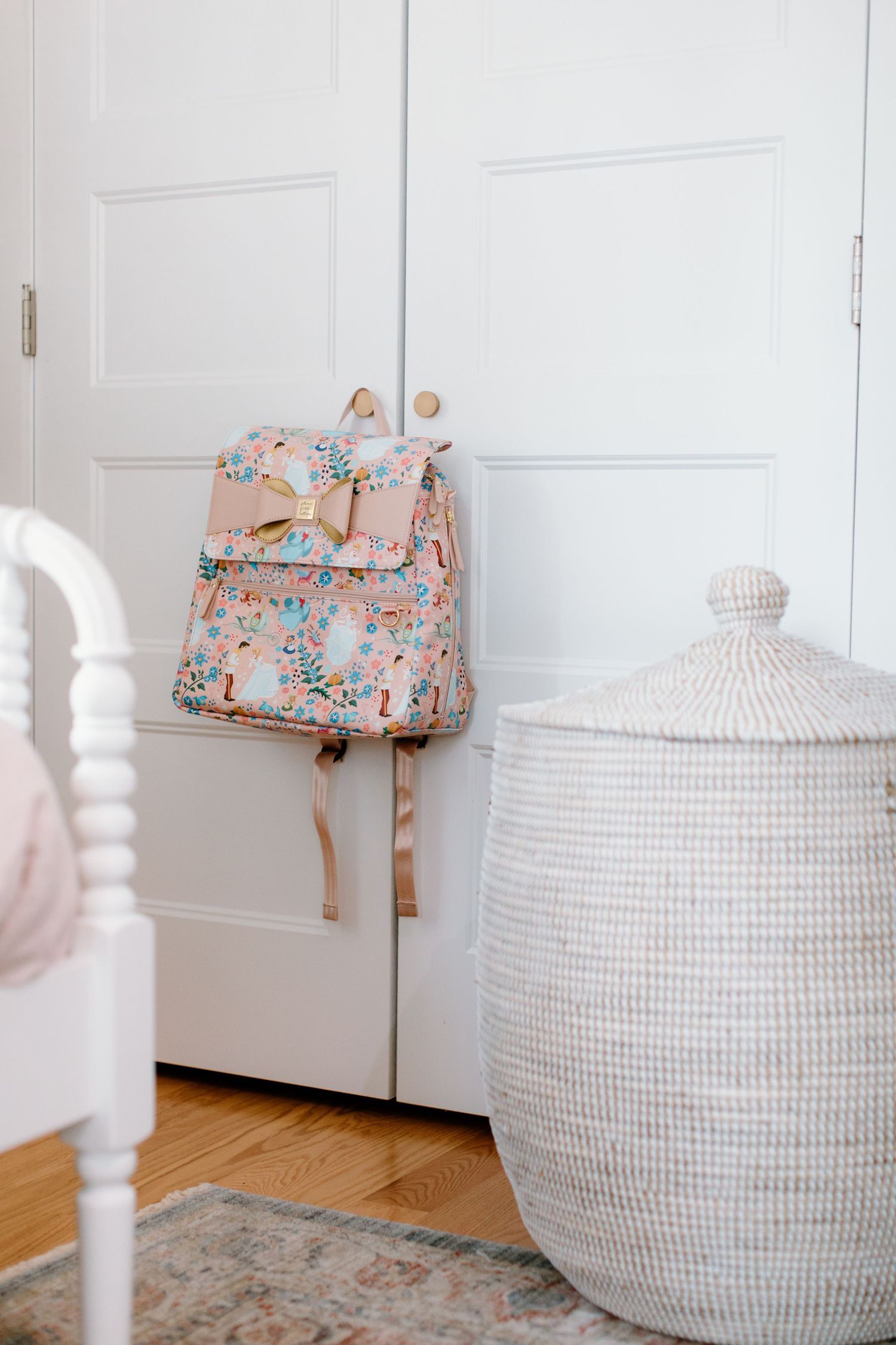 White woven storage baskets with floral bags on hardwood floor.