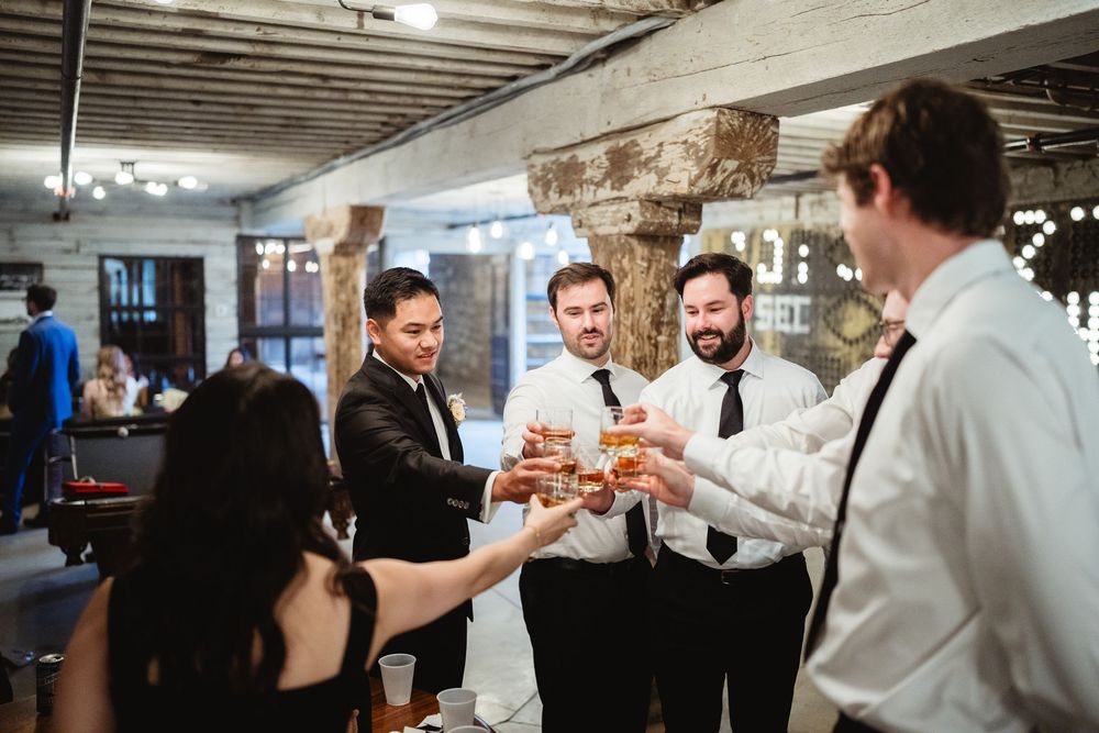 A group of people stand together holding up drinks and toasting at what appears to be a celebration or party.