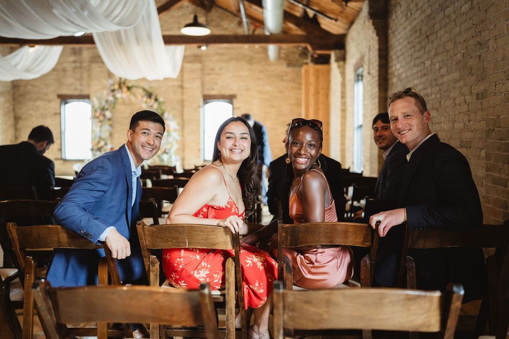 Wedding reception venue interior features an elegant exposed brick wall and wooden tables with white tablecloths and chairs.