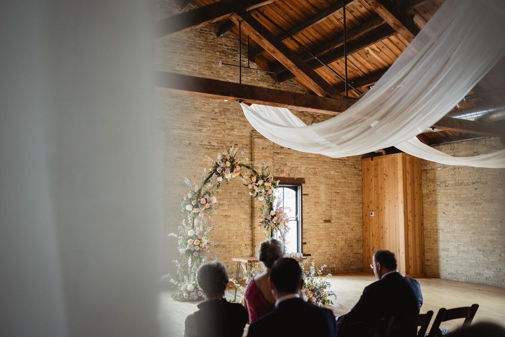 Elegant rustic barn venue interior decorated with white fabric draping and florals for a wedding celebration.