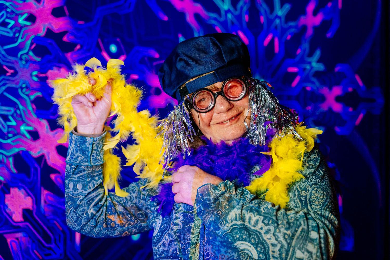 Dynamic event portrait of a person in a beanie and glasses under colorful blue and gold party lights.Modem festival