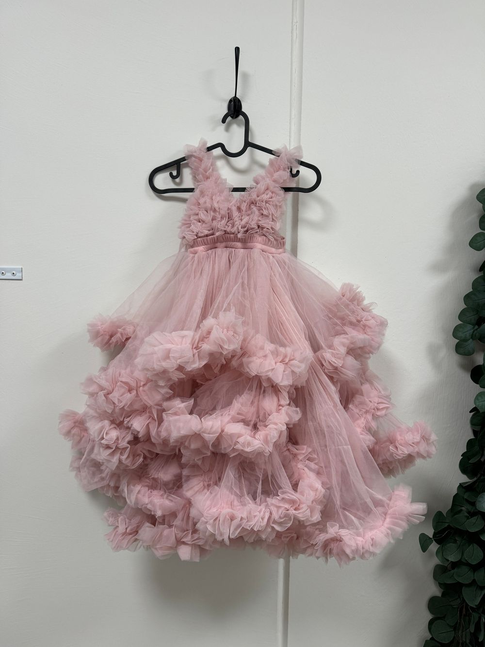 Fluffy pink tulle pettiskirt with layers of ruffles shown from different angles against a white wall.