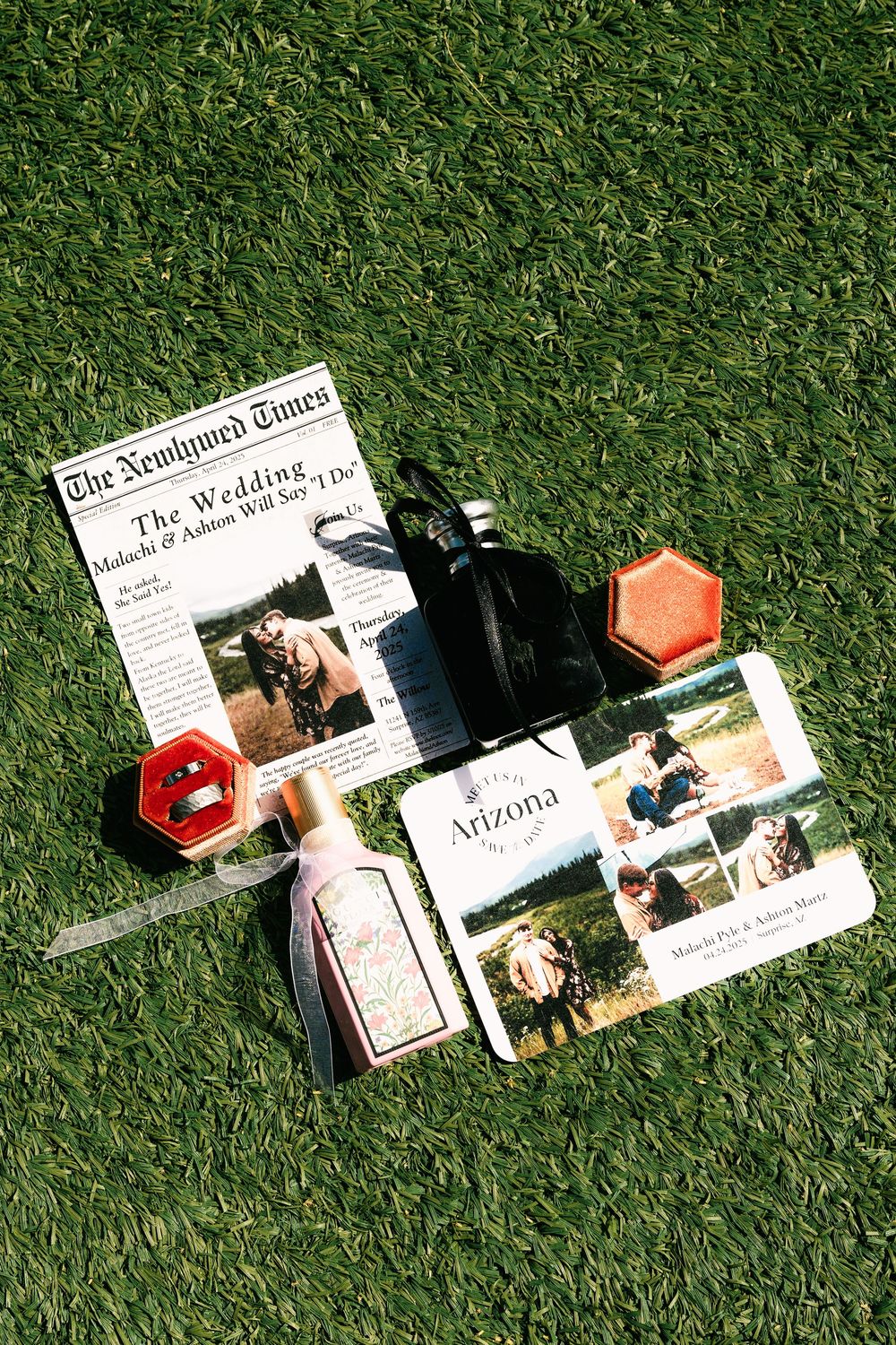 Wedding details flatlay with newspaper, invitations, and decor items on artificial grass.