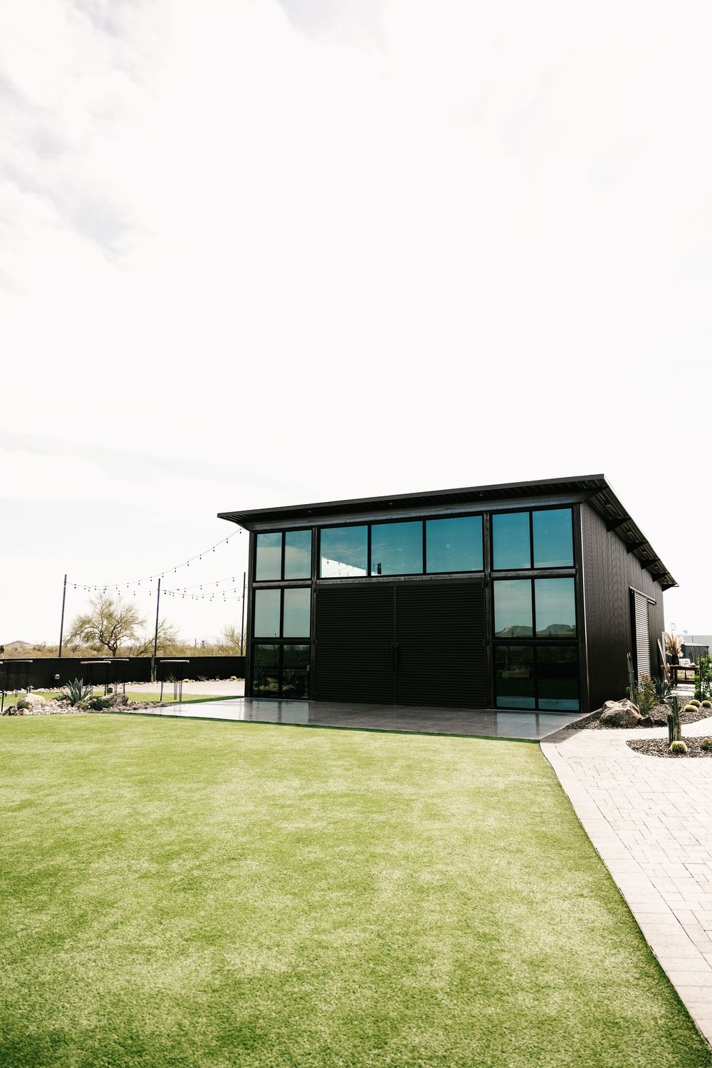 Modern black wedding venue building with glass windows and manicured lawn.