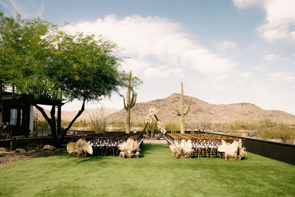 Outdoor desert wedding ceremony setup with mountain backdrop and natural landscaping.